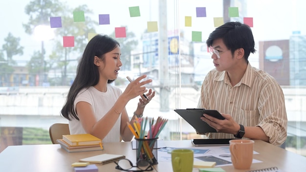 Geconcentreerde jonge vrouw en haar collega bespreken samen nieuwe marketingstrategie