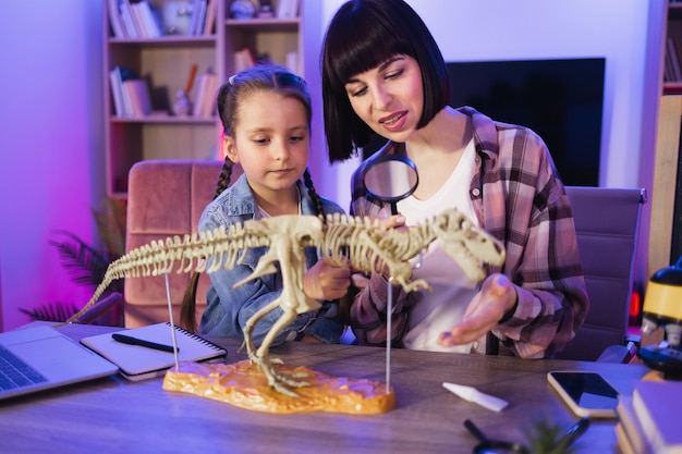 Geconcentreerde jonge vrouw onderzoekt het skelet van een dinosaurus met een vergrootglas