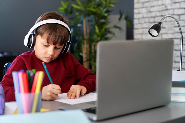 Geconcentreerde jongen die huiswerk doet tijdens e-learning