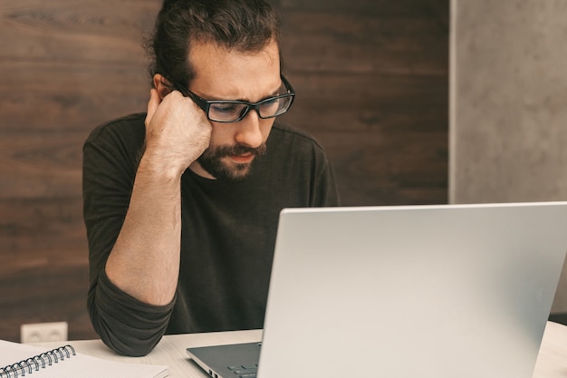 Geconcentreerde man die thuis werkt met laptop