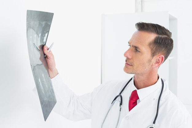 Foto geconcentreerde mannelijke arts die röntgenstraal onderzoekt