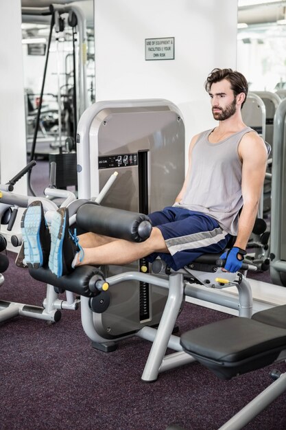 Geconcentreerde mens die gewichtenmachine voor benen met behulp van bij de gymnastiek