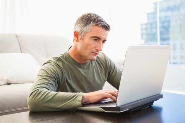 Geconcentreerde mens met grijs haar die laptop met behulp van