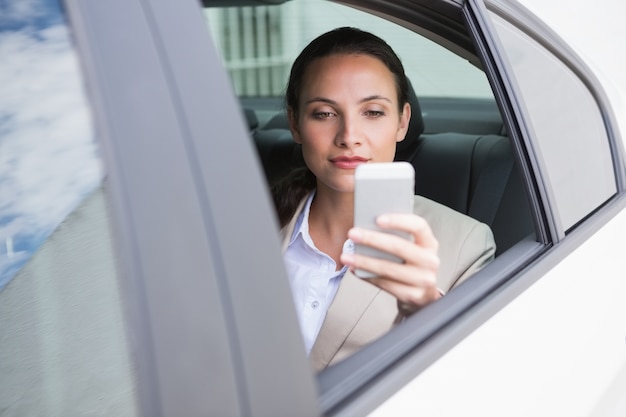 Geconcentreerde onderneemster die haar telefoon met behulp van