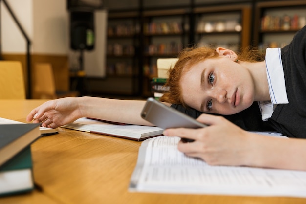 Geconcentreerde roodharige tienermeisje studeren