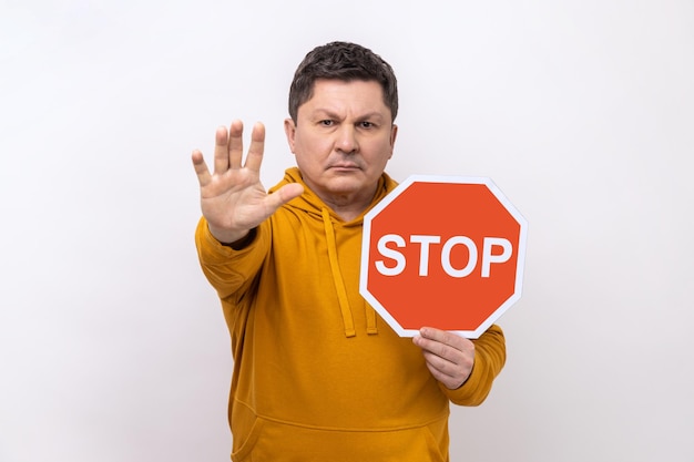 Geconcentreerde serieuze man die boos kijkt en een stopgebaar toont met verkeersbord