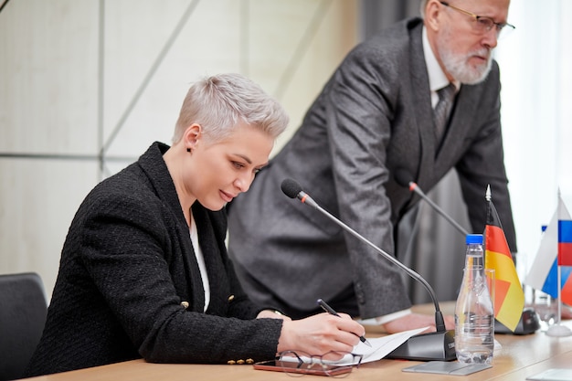 Geconcentreerde serieuze vrouw in pak op conferentie, luisterend naar gesprekken van partners, op multi-etnische bijeenkomst zonder banden. zaken, top concept