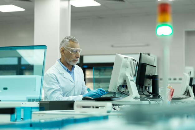 Geconcentreerde volwassen wetenschapper die naar het scherm van de computer staart