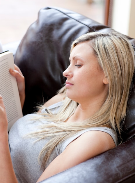 Geconcentreerde vrouw die een boekzitting op een bank leest