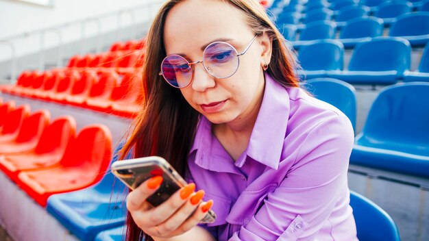 Geconcentreerde vrouw die mobiele telefoon op tribune gebruikt