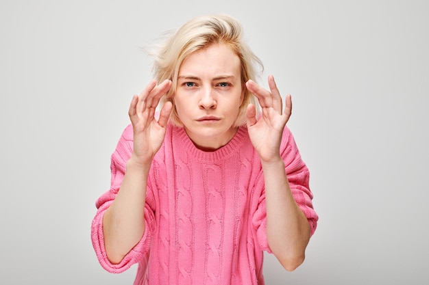 Geconcentreerde vrouw in roze trui met geconcentreerde uitdrukking probeert te luisteren overhoor gesprek