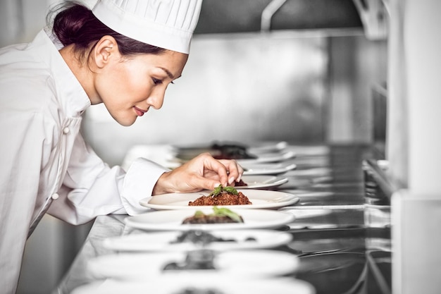 Foto geconcentreerde vrouwelijke chef-kok die voedsel in keuken versieren