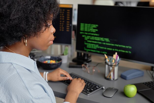 Geconcentreerde vrouwelijke programmeur die aan de computer werkt