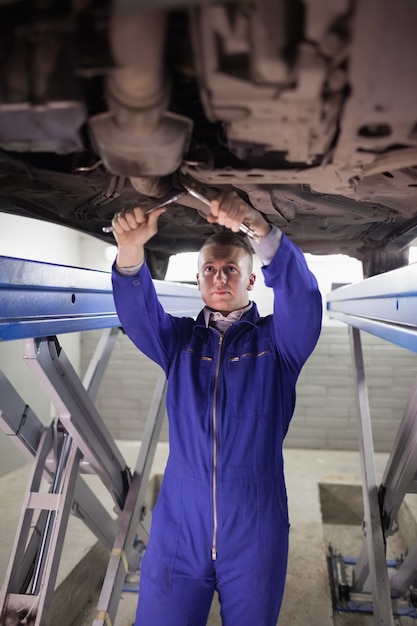 Geconcentreerde werktuigkundige die een auto met moersleutels herstelt
