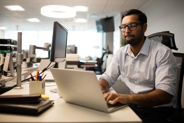 Geconcentreerde zakenman die op laptop in bureau werkt