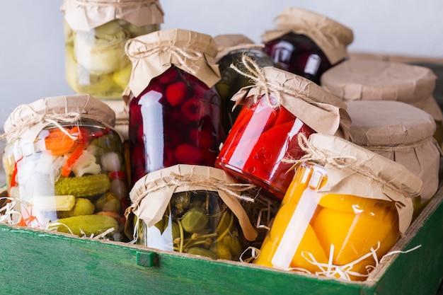 Foto geconserveerd en gefermenteerd lokaal voedsel. assortiment zelfgemaakte potten met een verscheidenheid aan ingemaakte en gemarineerde groenten, fruitcompote op een houten tafel. huishouden, huishoudkunde, oogstbehoud