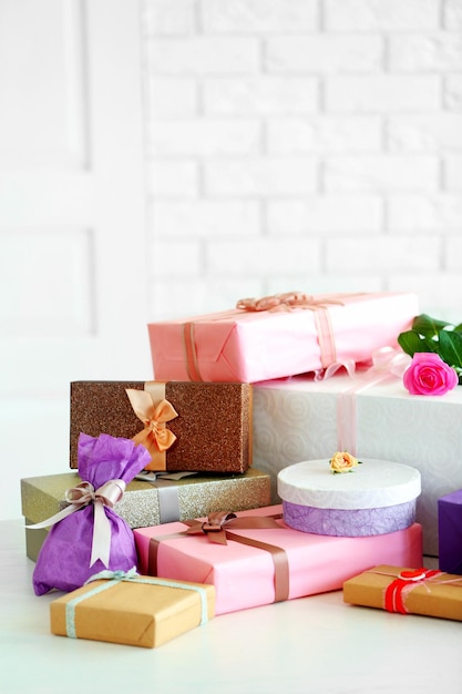 Gedecoreerde geschenkdozen en bloemen op tafel voor witte bakstenen muur achtergrond