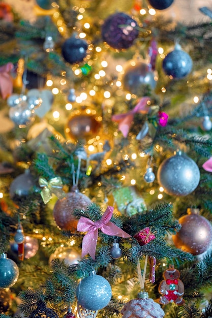 Gedecoreerde kerstboom close-up met sprankelende kerstballen en bokeh kerstverlichting roze boog en glitter...