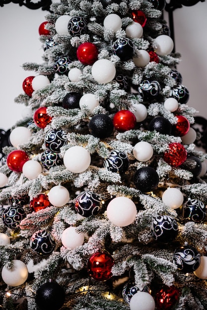 Gedecoreerde kerstboom close-up. Rode en witte ballen en slingerlichten met lantaarns. Kerstversiering voor de wintervakantie