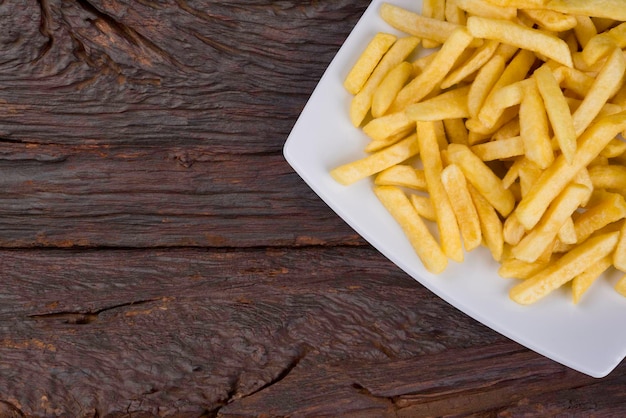 Gedeelte van Franse frietjes in witte plaat over oud hout