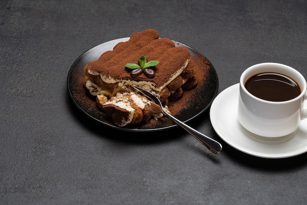 Gedeelte van klassiek tiramisudessert en kopje verse espressokoffie op concrete achtergrond of tafel