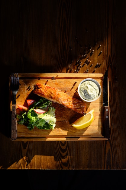 Gedeelte van zalmfilet met kruiden op een houten lijst. Bovenaanzicht