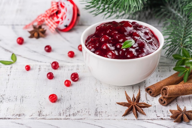 Gedeelte van zelfgemaakte cranberrysaus Cranberryjam in witte keramische kom Kopieer ruimte