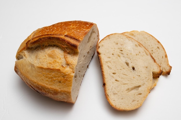 Gedeeltelijk gesneden brood van de tarwe zuurdesem haard brood met zemelen op een witte achtergrond