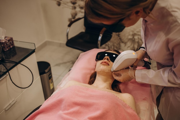 Gedeeltelijke mening van jonge vrouw die epilatie van de laserhaarverwijdering op gezicht in salon ontvangt