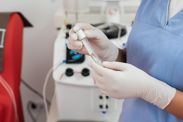 gedeeltelijke weergave van een multiraciale gezondheidszorgmedewerker in blauw uniform en latexhandschoenen die een testbuis vasthoudt