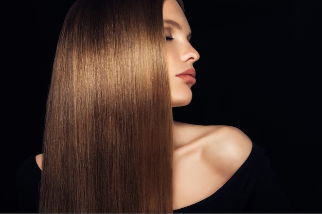 Gedeeltelijke weergave van glimlachende vrouw met glanzend gezond en sterk haar geïsoleerd op zwart