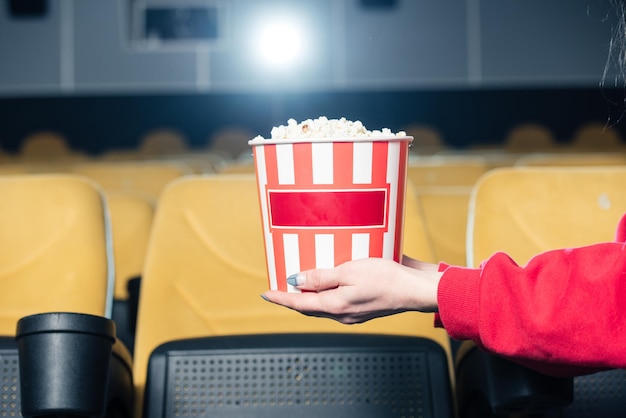 Gedeeltelijke weergave van kind met gestripte papieren beker met popcorn in de bioscoop