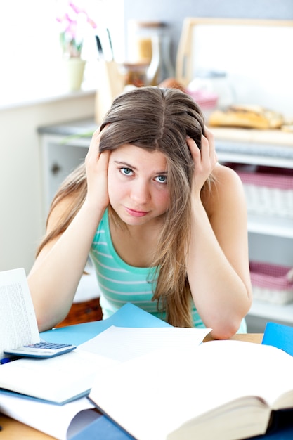 Foto gedeprimeerde student die haar thuiswerk op een bureau doet