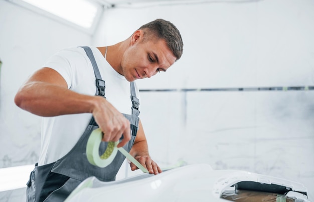 Gedetailleerd werk Blanke autoreparateur in uniform heeft baan in garage