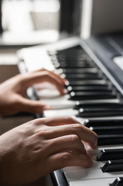 Gedetailleerde weergave van de handen van een jonge donkerharige man die de elektronische piano of synthesizer bespeelt