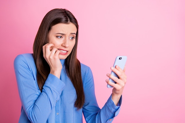 Gedraaide foto van de teleurgestelde droevige holding van de studententelefoon met handen die spijkers bijten