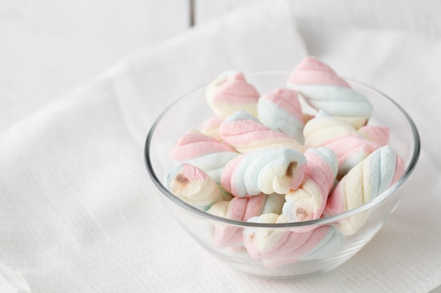 Gedraaide marshmallows in een kopje, over houten muur.