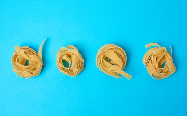 Gedraaide pasta in ronde fettuccine nesten op een blauwe achtergrond