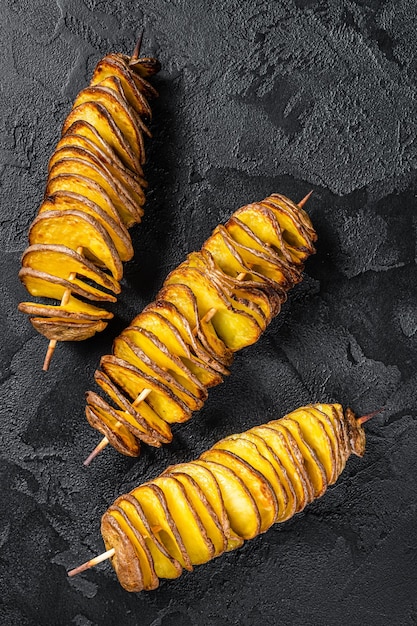 Gedraaide tornado-aardappelchips. Zwarte achtergrond. Bovenaanzicht.