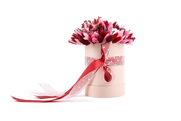 Gedroogd bloemboeket met grassen in roze ronde hoedendoos geïsoleerd op een witte achtergrond