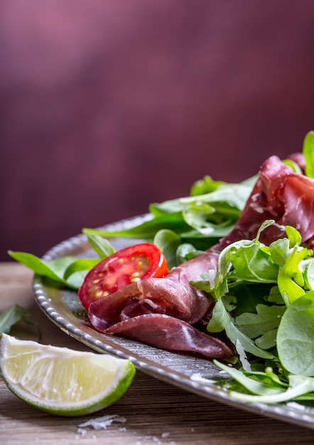 Gedroogd rundvlees bresaola. Salade bresaola rucola baby spinazie tomaten limoen en kaas Parmezaanse kaas.