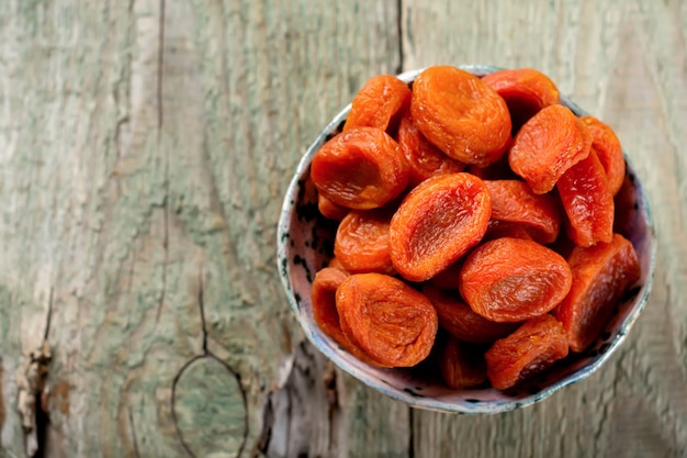 Gedroogde abrikozen in een bamboekom op oude houten. gezond gedroogd fruit