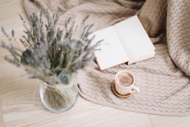 Gedroogde bloemen en een kopje cappuccino met boek op houten achtergrond bovenaanzicht