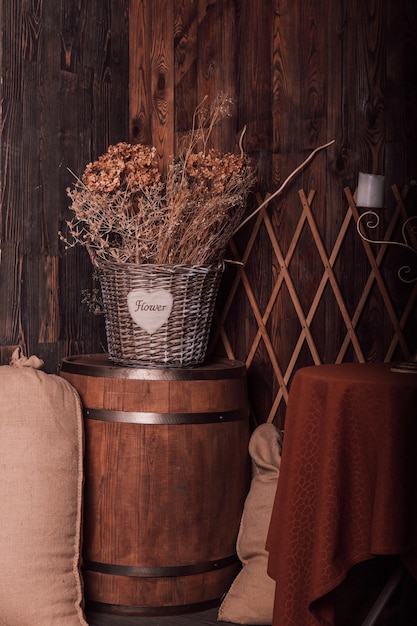 Gedroogde bloemen in een rieten mand op een houten vat in retro stijl