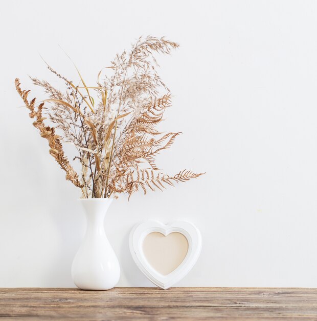 Foto gedroogde bloemen in vaas op houten tafel op witte achtergrond