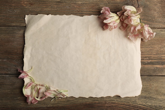 Gedroogde bloemen op vel papier op houten tafel, bovenaanzicht