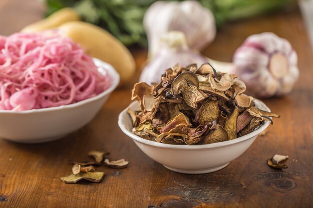 Gedroogde champignons zure kool knoflook en aardappelen op houten tafel.