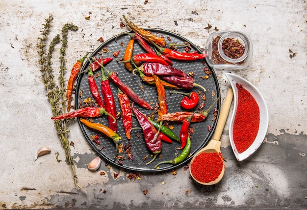 Gedroogde chilipepers op een dienblad met gemalen rode peper in de cups, met kruiden