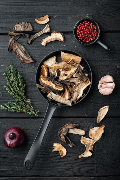 Foto gedroogde eekhoorntjesbrood in gietijzeren koekenpan, op zwarte houten tafel achtergrond, bovenaanzicht plat lag