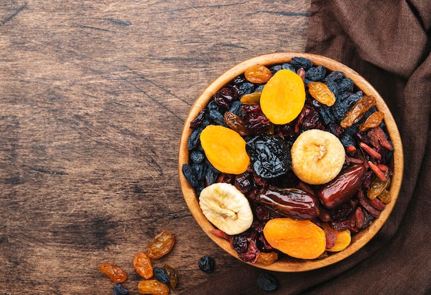 Gedroogde fruitschaal Gezonde voeding snack zongedroogde biologische mix van abrikozen, vijgen, rozijnen, dadels en andere op houten tafelblad